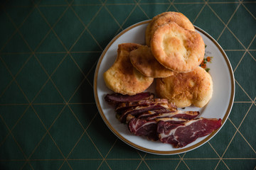 A plate of dried meat and buns.