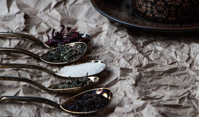 Black tea cup with golden spoons and green, black and carcade tea, drink and beverage photo in dark mood and craft style photo