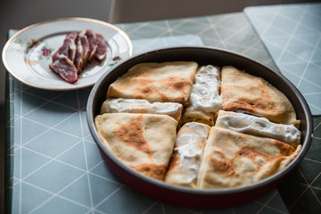 Food preparing in a countryside. Stuffed pancakes, cream and dried meat.