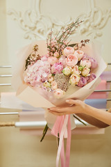 cropped view of florist holding bouquet of roses and peonies at workspace