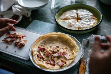Food preparing in a countryside. Stuffed pancakes, cream, cheese, dried meat and bacon.