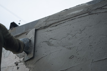 Hands of an old manual worker with wall plastering tools