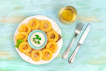 Calamari rings with mayonnaise and a glass of white wine, shot from the top on a teal background with copy space