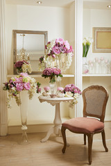 Interior of room with chair, mirror, bouquets in glass vases