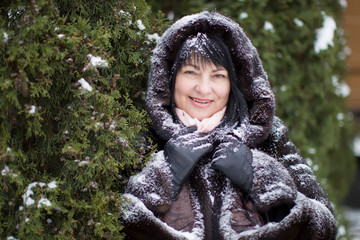 Elderly woman in a fur hood covered with snow