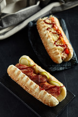Two hot dogs on black background. Junk food