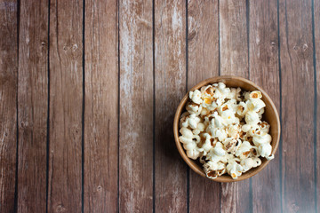 Salt popcorn on the wooden table. Popcorn in a wooden bowl.