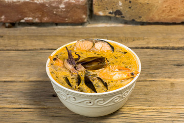 Freshly cooked seafood bouillabaisse soup with shrimps, fish fillets and mussels closeup in a bowl on the table.
