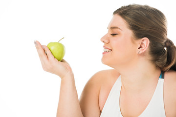 Obraz na płótnie Canvas young smiling overweight woman looking at green apple isolated on white