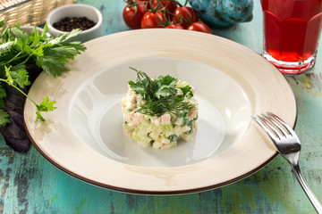 Traditional Russian salad Olivier with parsley on top on on blue wooden table