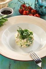 Traditional Russian salad Olivier with parsley on top on on blue wooden table
