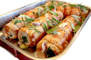 close up of stuffed pork with spinate cooked in the oven with herbs and garlic served with sauce and potatoes.   