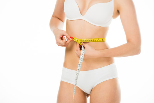 cropped view of slim woman in underwear measuring waist with centimeter isolated on white