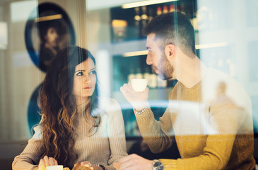 Couple drinking an espresso. Reflected between the window.