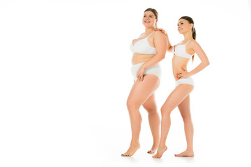 happy slim and overweight women in underwear posing together isolated on white, body positivity concept