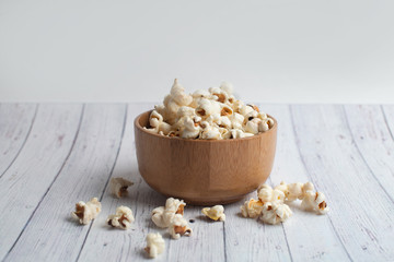 Salt popcorn on the wooden table. Popcorn in a wooden bowl.
