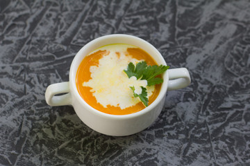 pumpkin soup puree with cream and parsley on grey background