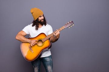 Obraz premium Portrait of his he nice handsome attractive cheerful confident wavy-haired guy playing guitar hit pop rock composition isolated over gray pastel background
