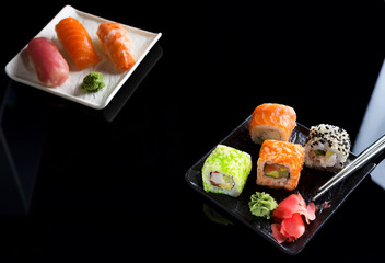 Large sushi sets with lots of sushi, roll . Stylish sushi sets on a black ceramic plane and table with Chinese sticks. Copy space