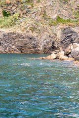 Italy, Cinque Terre, Monterosso, a group of people on a rock next to a body of water