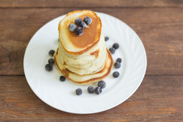 stack of pancakes with black currant berries on wooden background