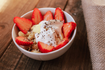 strawberries with yogurt seeds pumpkin seeds chia sunflower seeds and apple in a white bowl on a wooden table