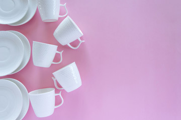 Overhead flat lay view of white clean tableware on pink background