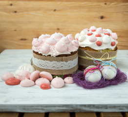 Easter, holiday cakes, meringue sweets, flowers natural background, painted eggs in a nest, on a wooden table.
