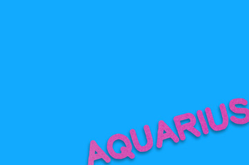 Word aquarius cut out of purple paper on blue table. Top view. Horoscope concept