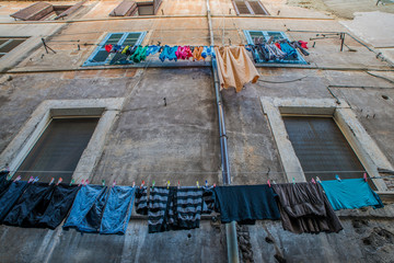Hanging laundry at the laundry line in front of the window in Italy.