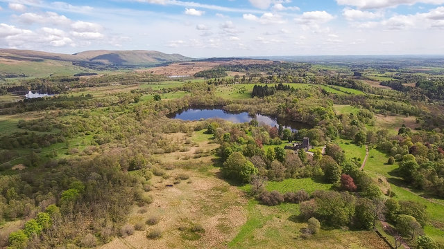 Aerial image over Mugdock Castle and country park towards distant hills.