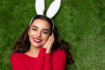 Pretty girl in bunny ears lying on meadow 