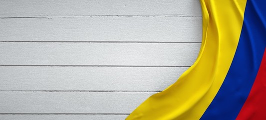 Flag of Colombia, on top of white wood. Wrinkled fabric.