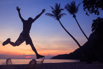 Asian man jumping fun on the beach at sunrise