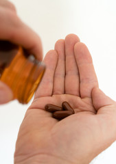 pillbottle and large brown pills in the palm of a man's hand