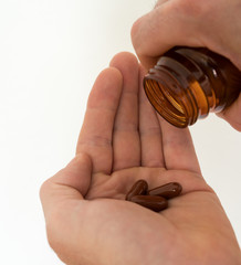 pillbottle and large brown pills in the palm of a man's hand