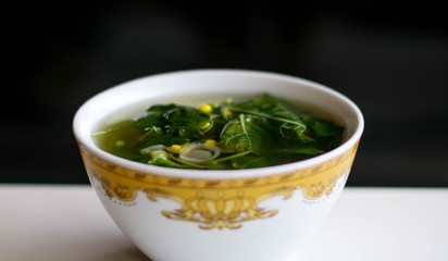 Sayur Bening Bayam or Spinach Clear Soup on white background. Boiled spinach with corn. Indonesian food.