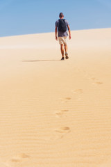 Fototapeta na wymiar young backpacker man walking by the desert
