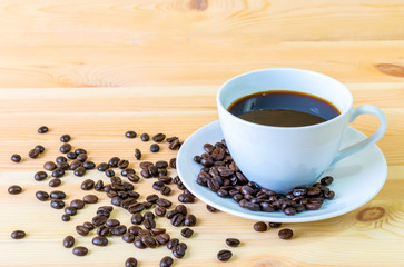 Coffee cup and coffee beans on table with wooden background and copy space for advertisers.