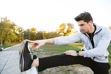 Confident healthy sportsman doing stretching exercises