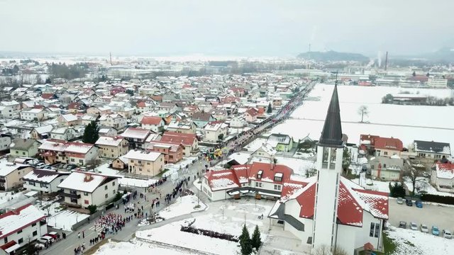 A beautiful town in winter time. Aerial shot. The parade with different cosumes is taking place today.
