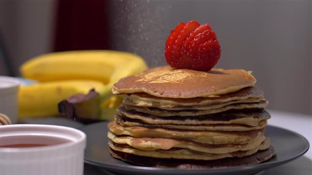 Sprinkling of American pancakes with powdered sugar. Slow Motion