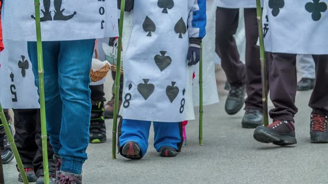 Young and old are dressed in 'cards' costumes and they are walking in the parade.