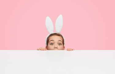 Cute girl in ears hiding behind table 