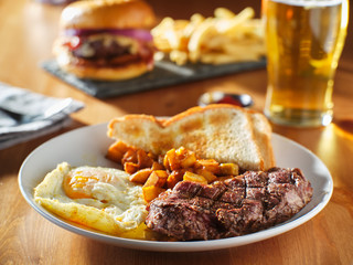 steak and eggs breakfast with toast and homestyle potatoes in restaurant