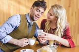 beautiful couple holding coffee cups and using smartphone at cafe
