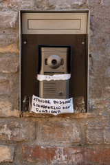 Handwritten sign attached to a doorbell - "Bell Not Working"