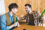 handsome and smiling men holding glass bottles of beer and talking