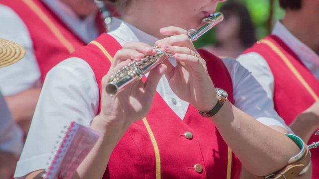 This young musician is playing a flute. The brass band is performing at the straw hat festival and fair.