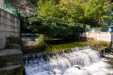 Fototapeta na wymiar a small artificial waterfall flowing from the lake of karst origin, located in the Republic of Abkhazia on the 13th kilometer of the road to lake Ritsa, on the right Bank of the river Bzyb
